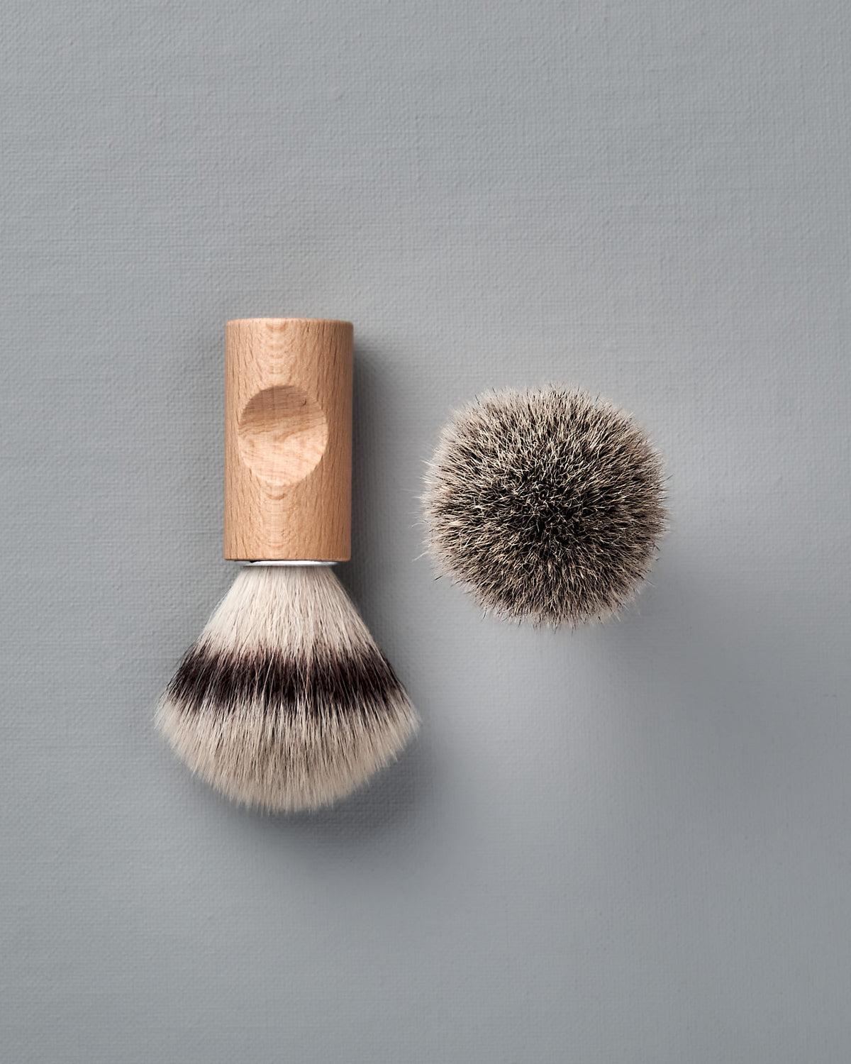 The Iris Hantverk Shaving Brush & Cup Set with Cedarwood Soap – Bundle features a wooden-handled brush and a top-down view of its bristles on a light gray surface, ideal for an elegant and classic shave.