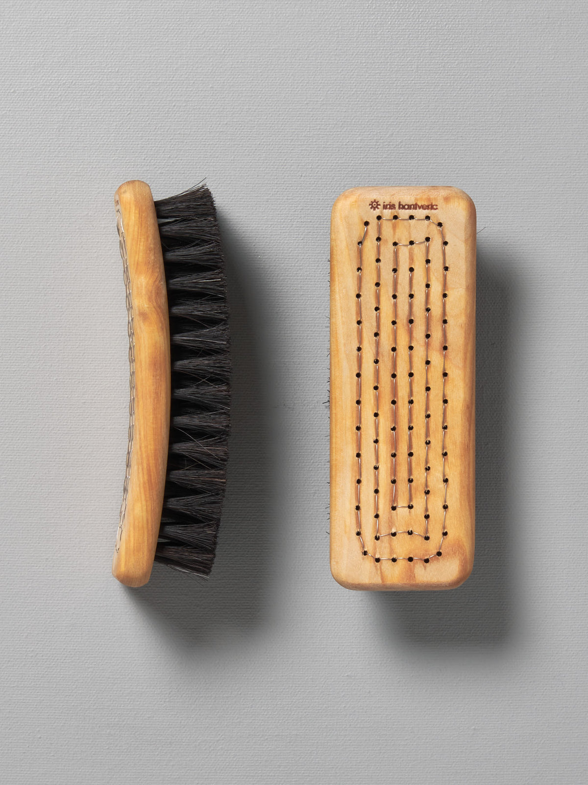 A pair of Iris Hantverk shoe brushes on a grey surface.
