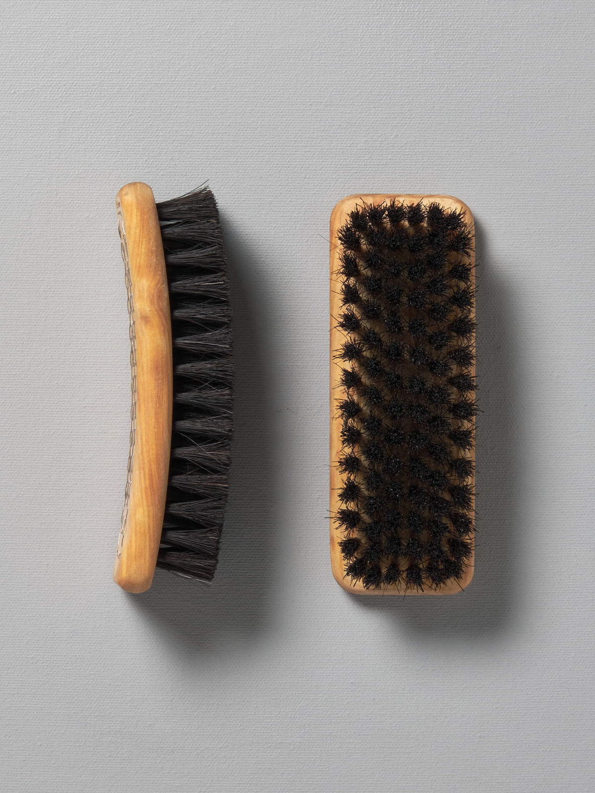 Two Iris Hantverk shoe brushes on top of each other on a grey surface.