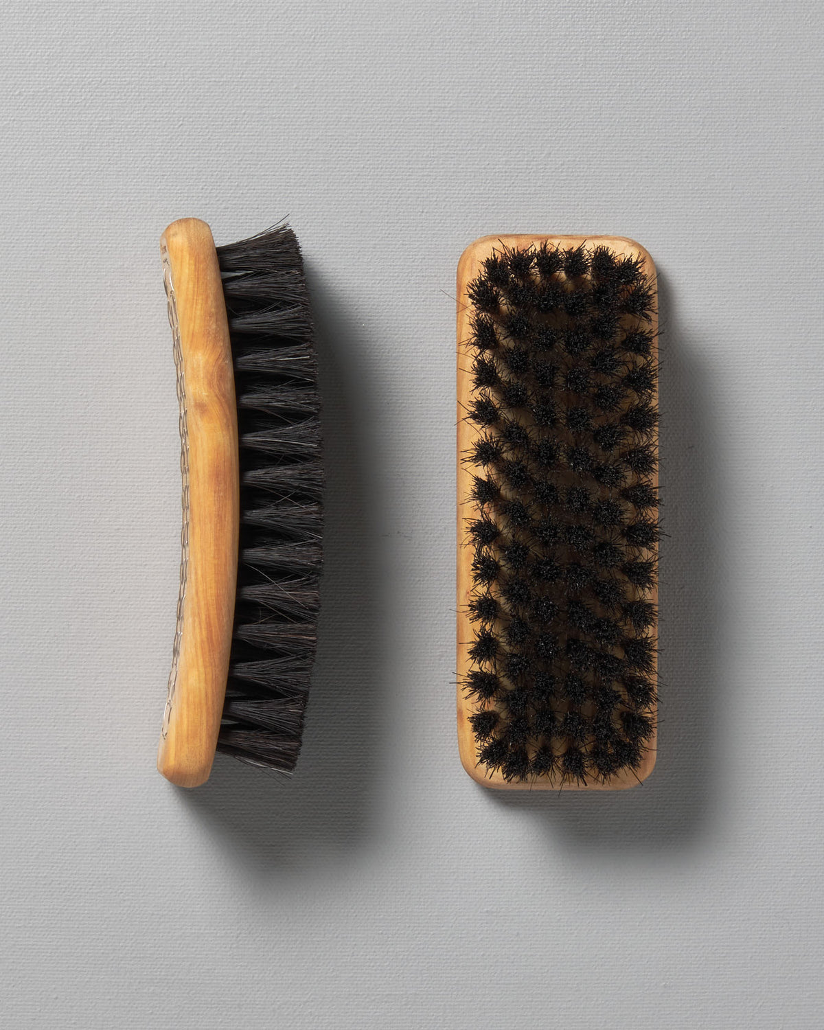 Two Iris Hantverk shoe brushes on top of each other on a grey surface.