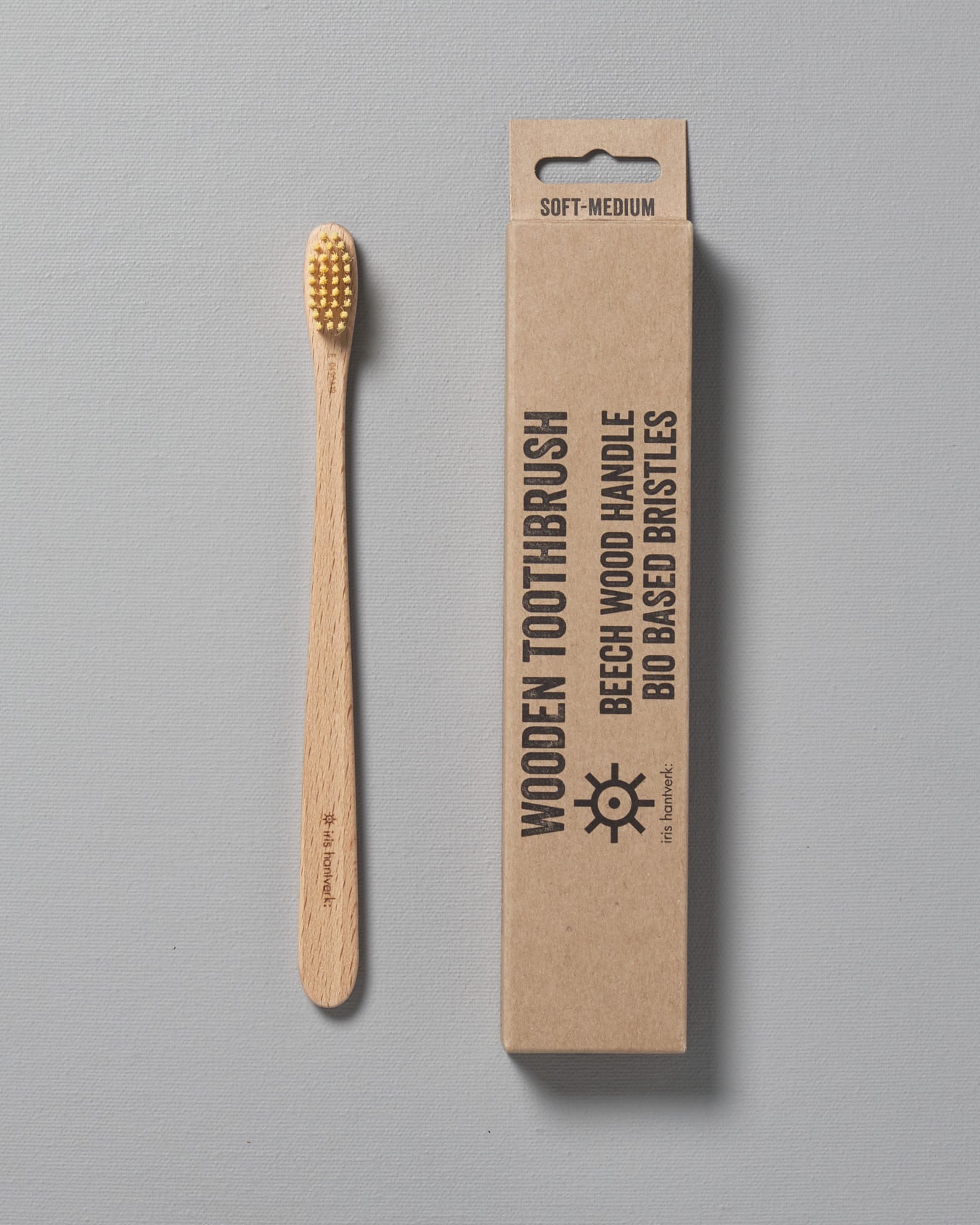 A wooden Iris Hantverk toothbrush next to a cardboard box.
