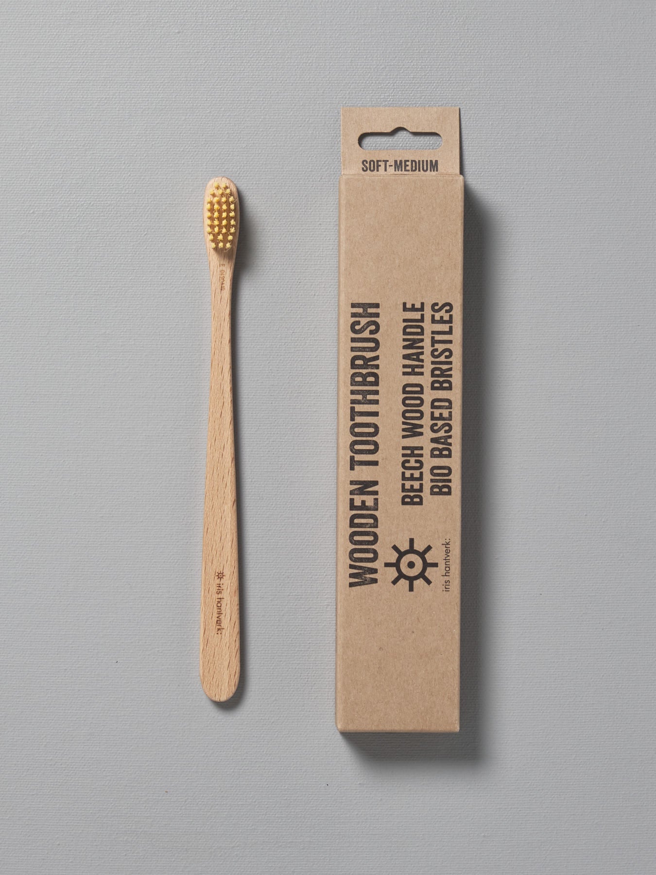A wooden Iris Hantverk toothbrush next to a cardboard box.