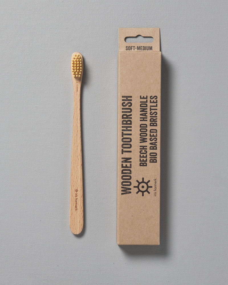 A wooden Iris Hantverk toothbrush next to a cardboard box.