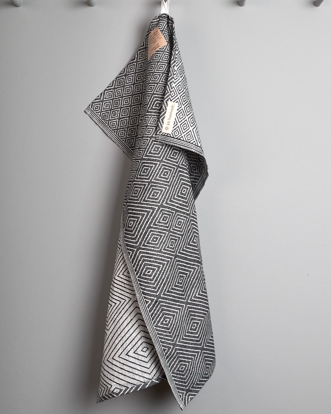 An Iris Hantverk black and white tea towel hanging on a hook.