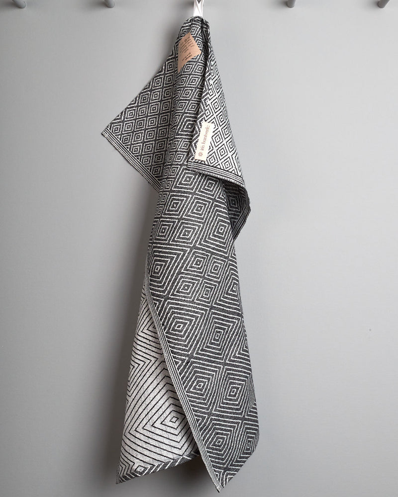 An Iris Hantverk black and white tea towel hanging on a hook.