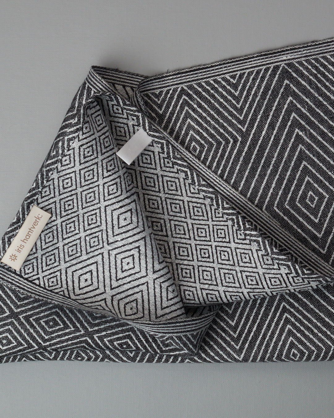 An Iris Hantverk black and white tea towel hanging on a hook.