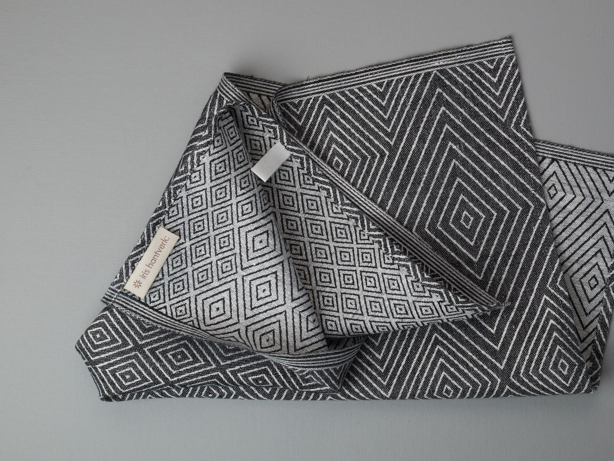An Iris Hantverk Linen Tea Towel – Black on a grey surface.