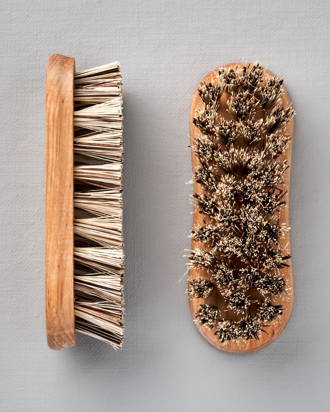 Two Iris Hantverk Vegetable Brushes on a grey background.