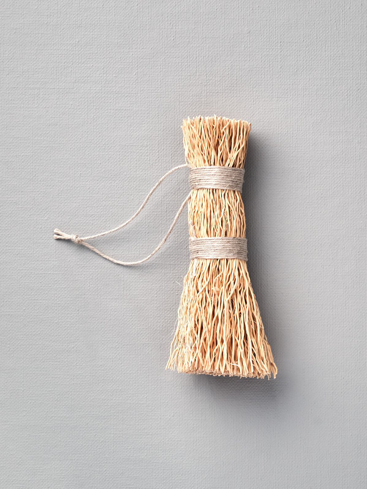 An Iris Hantverk Washing-up Whisk with a string attached to it.