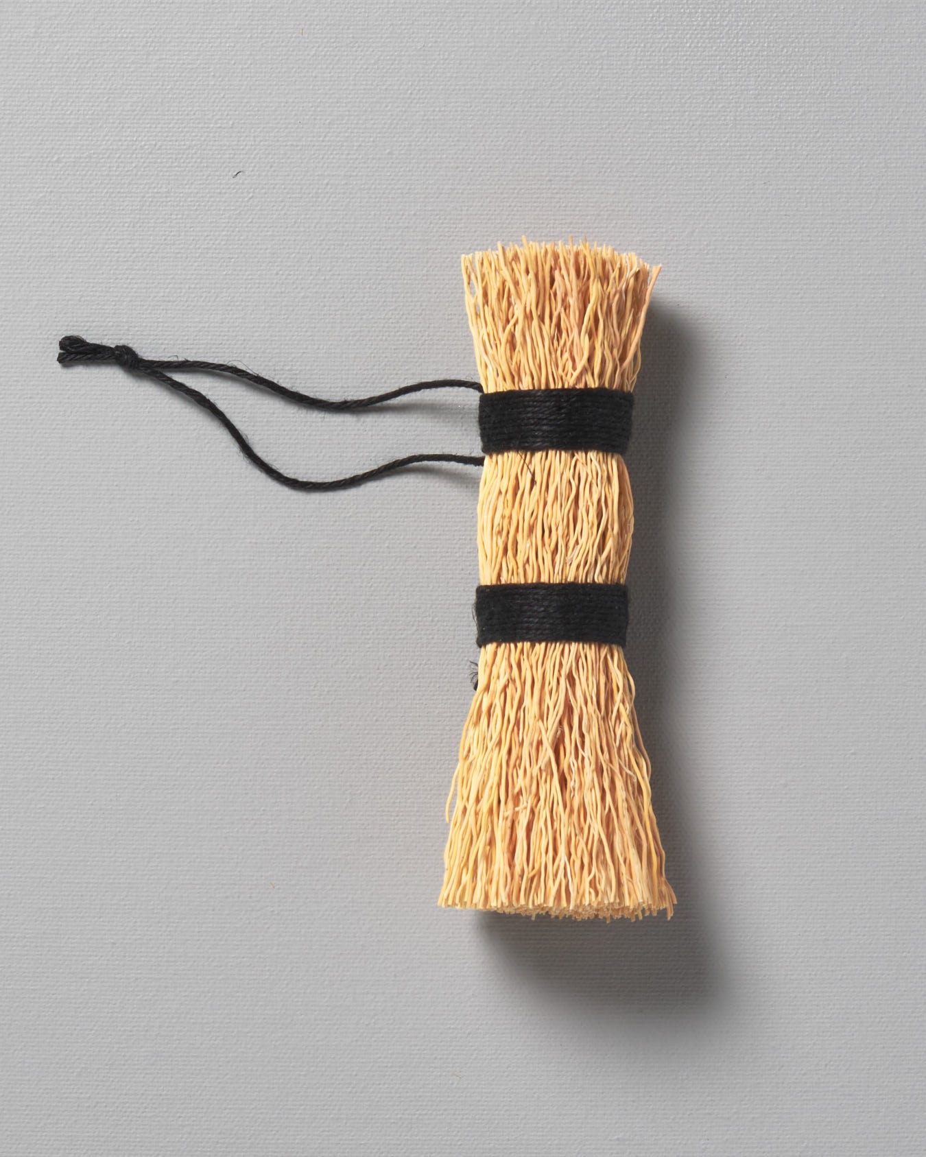 An Iris Hantverk Washing-up Whisk with a string attached to it.
