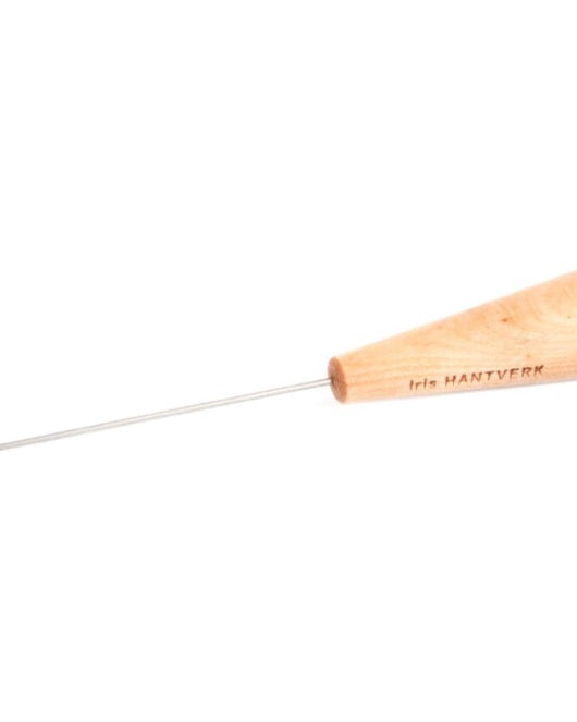 An Iris Hantverk Cake Tester with a wooden handle on a gray background.