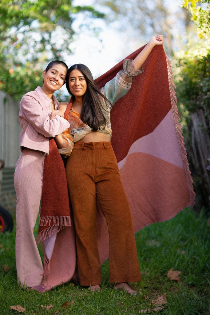 Two women standing next to each other holding a Seljak Brand Dune Blanket.