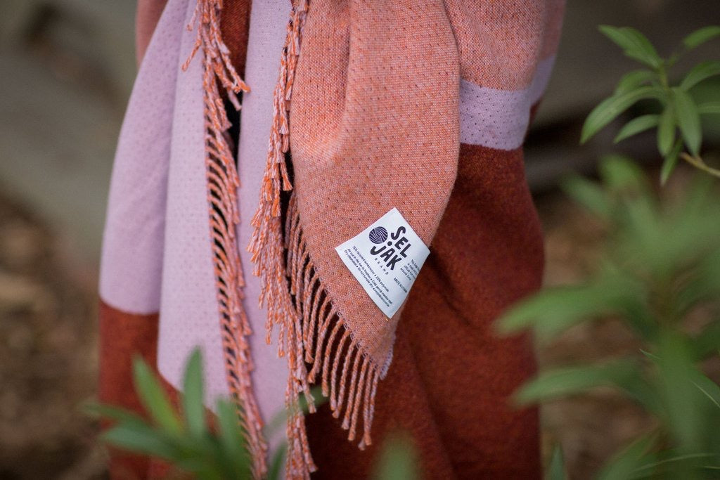 A pink and brown Dune Blanket hanging on a tree, made by Seljak Brand.