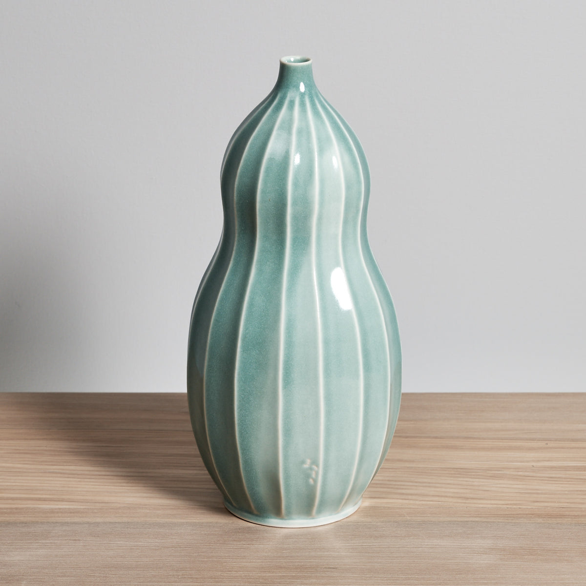 A Gourd Vase - Celadon by Jino Ceramic Studio on a wooden table.