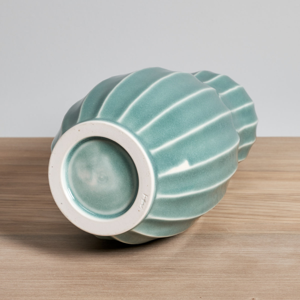 A Gourd Vase - Celadon from Jino Ceramic Studio sitting on top of a wooden table.