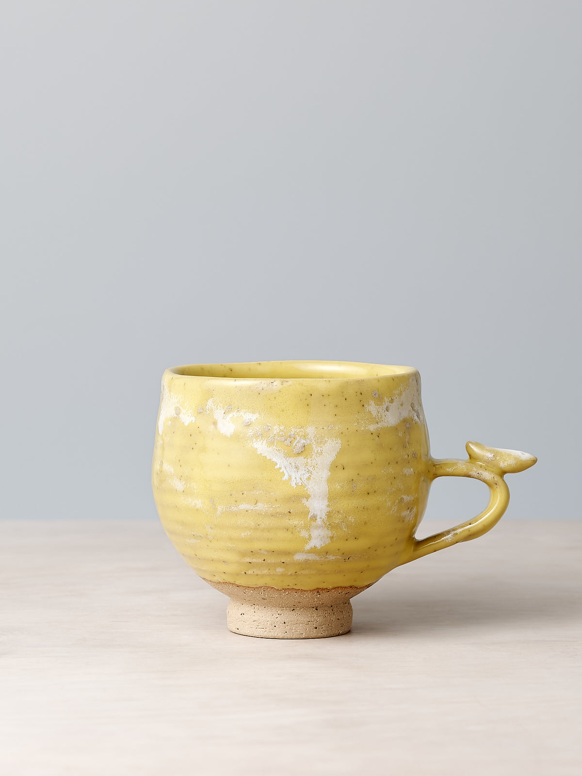 A Bird Handle Cup - Citrus by Jino Ceramic Studio sitting on a table.