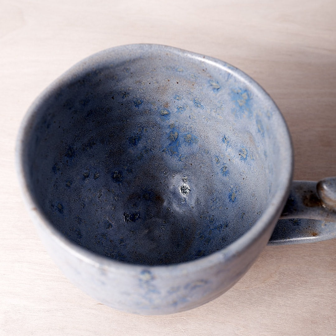 A Bird Handle Cup – Kokako with a handle on a wooden table.