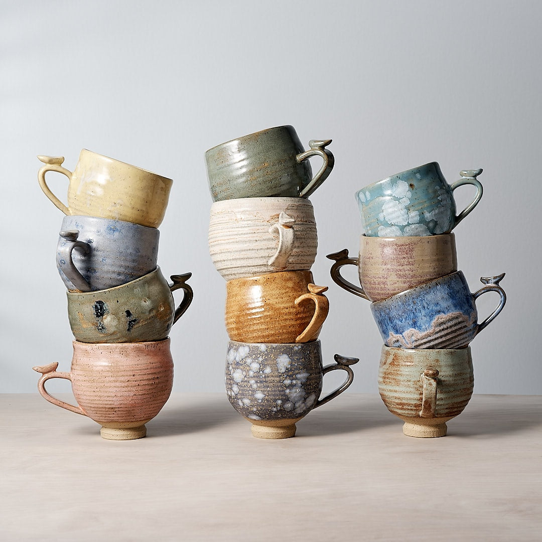 A stack of Bird Handle Cup – Green Tea mugs stacked on top of each other by Jino Ceramic Studio.