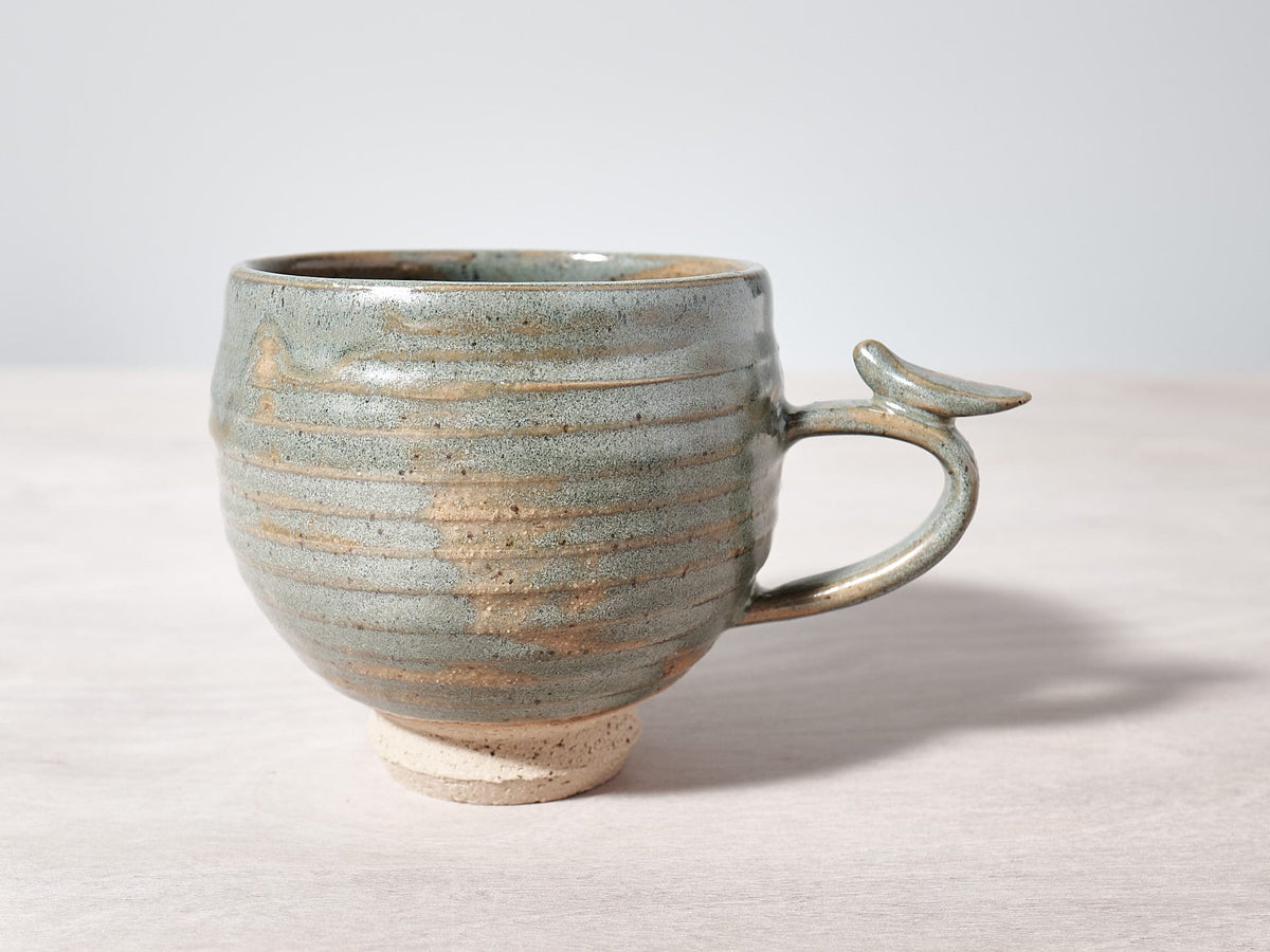 A Bird Handle Cup – Green Tea with a bird on it, made by Jino Ceramic Studio.