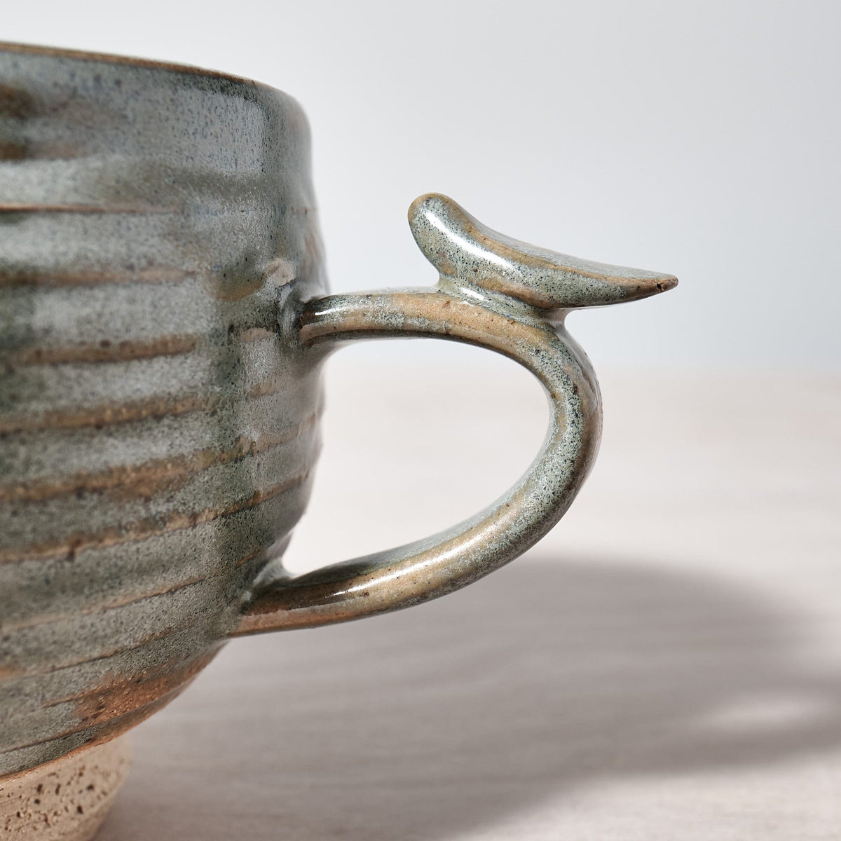 A Bird Handle Cup – Green Tea from Jino Ceramic Studio with a handle and a bird on it.