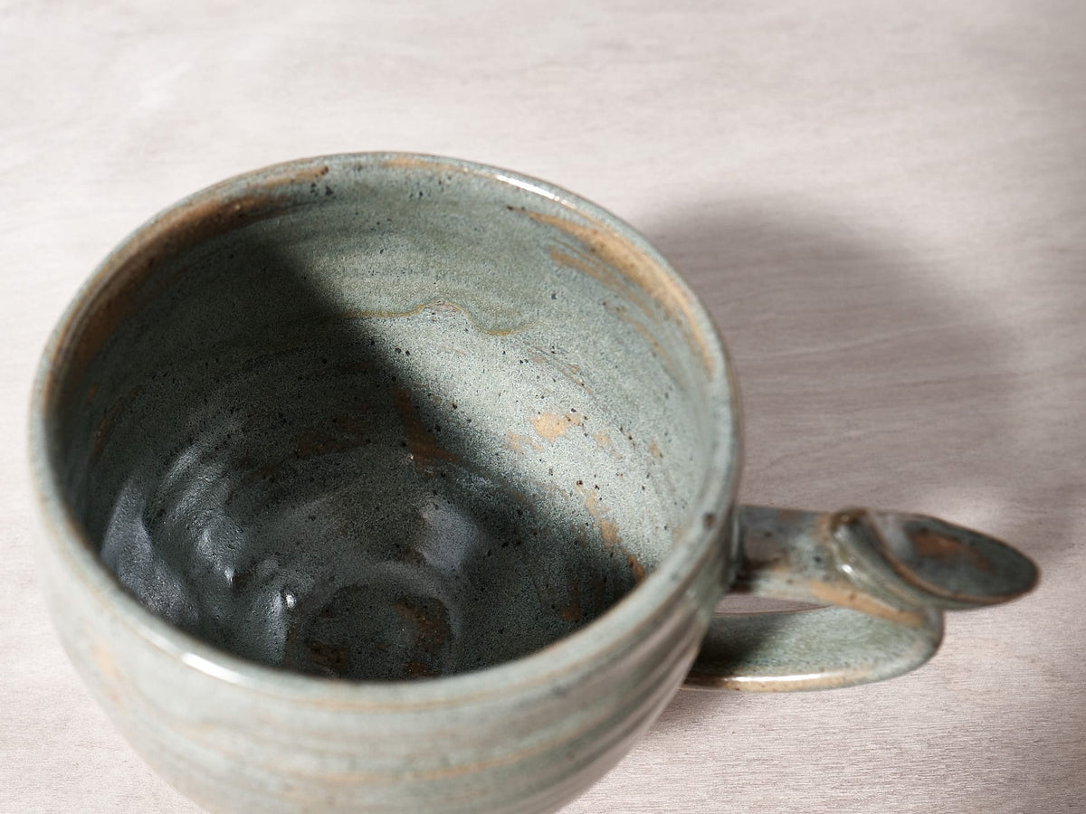 A Bird Handle Cup – Green Tea by Jino Ceramic Studio on a table.