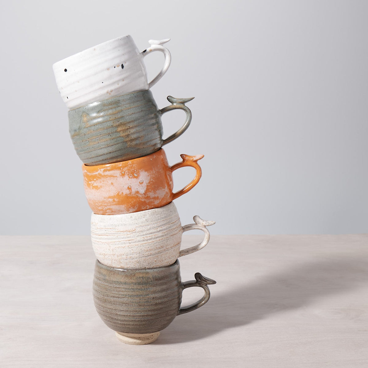 A stack of Bird Handle Cup - Green Tea mugs stacked on top of each other from Jino Ceramic Studio.