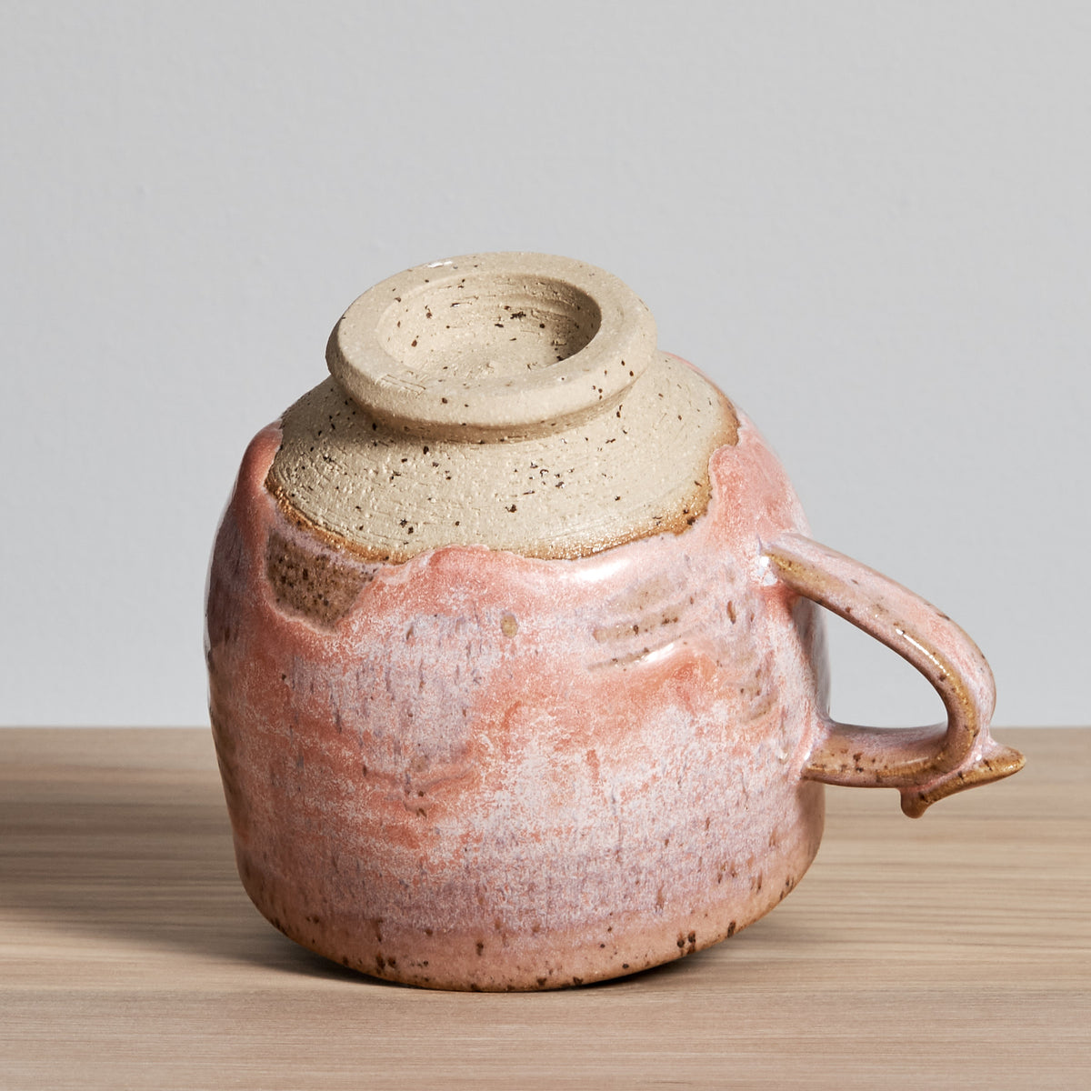A Bird Handle Cup - Rhubarb by Jino Ceramic Studio on a wooden table.