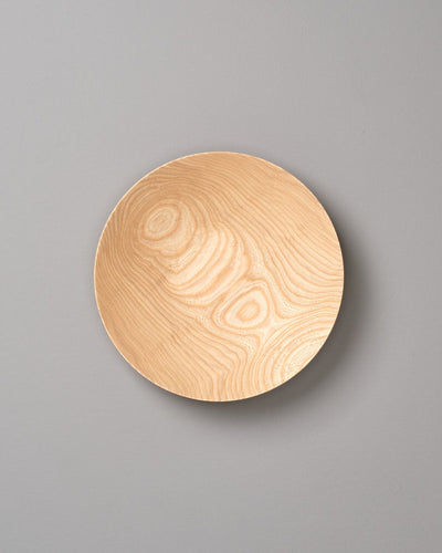 A round Kihachi wooden plate on a gray background.
