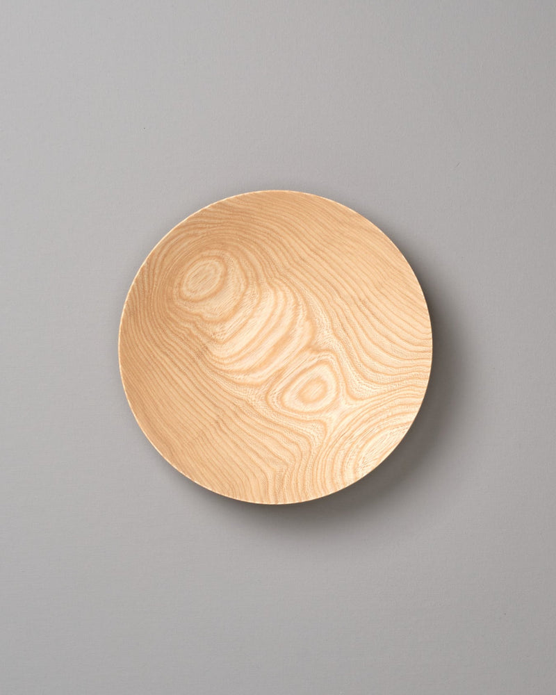 A round Kihachi wooden plate on a gray background.