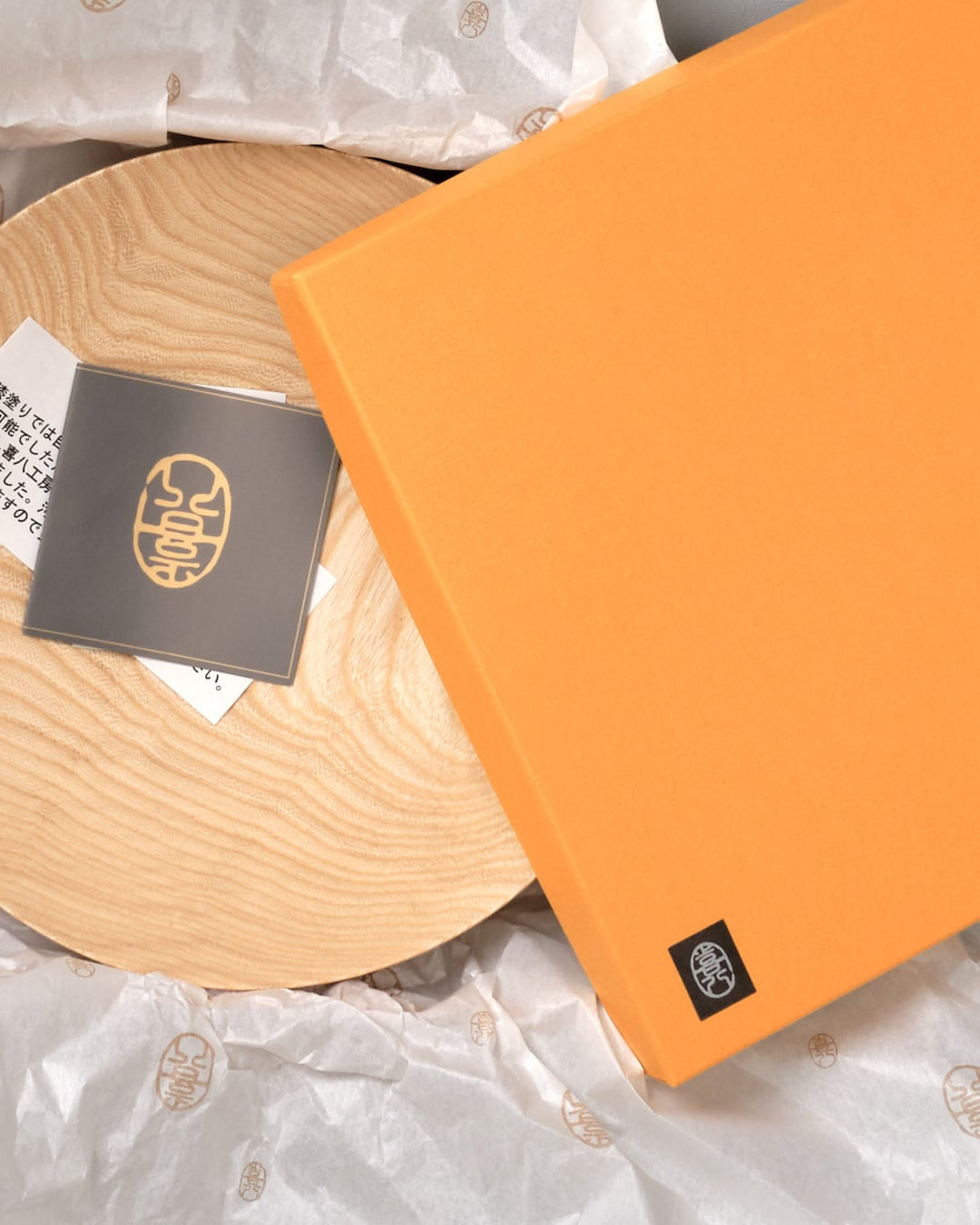 A round Kihachi wooden plate on a gray background.