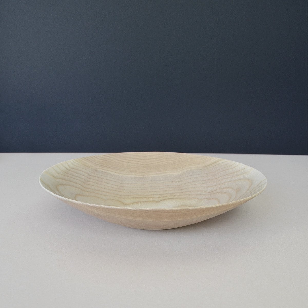 A Kihachi Wooden Plate - Small on a table with a dark background.