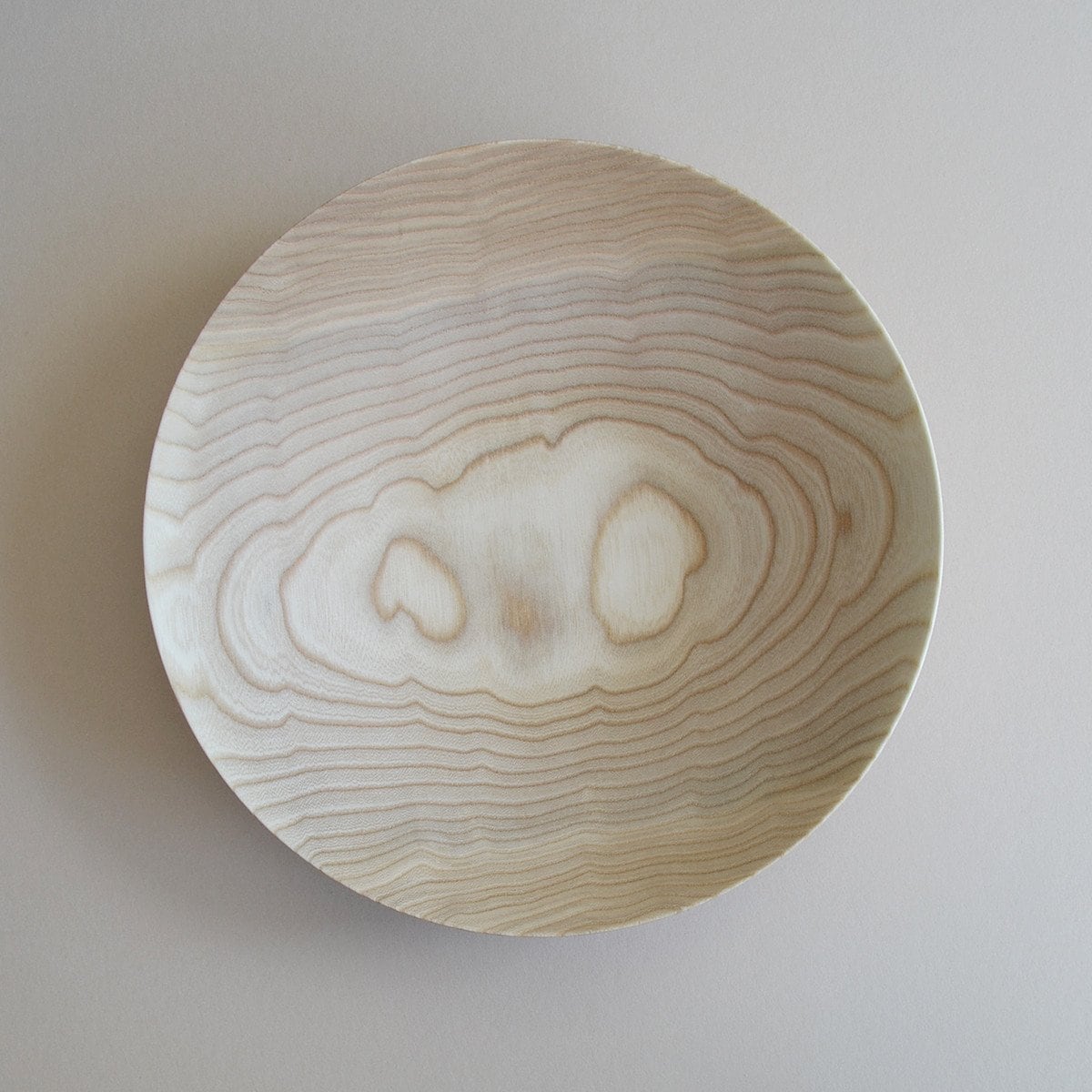 A Kihachi Wooden Plate - Medium with a pattern on it.
