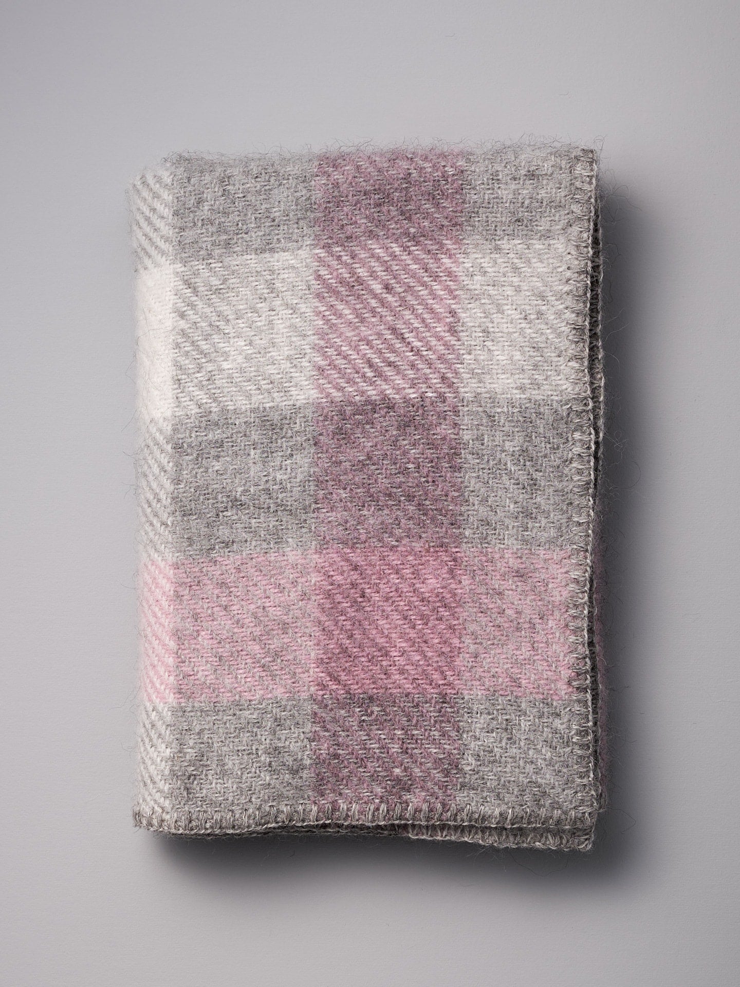 A Gotland Wool Baby Throw - Multi Pink blanket by Klippan on a grey surface.