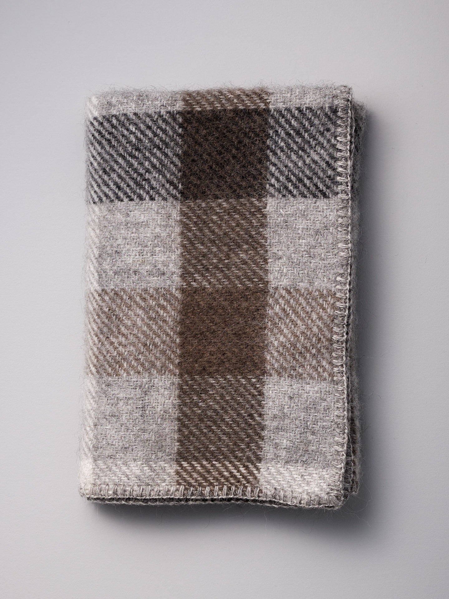 A Klippan Gotland Wool Baby Throw – Multi Grey blanket on a white surface.