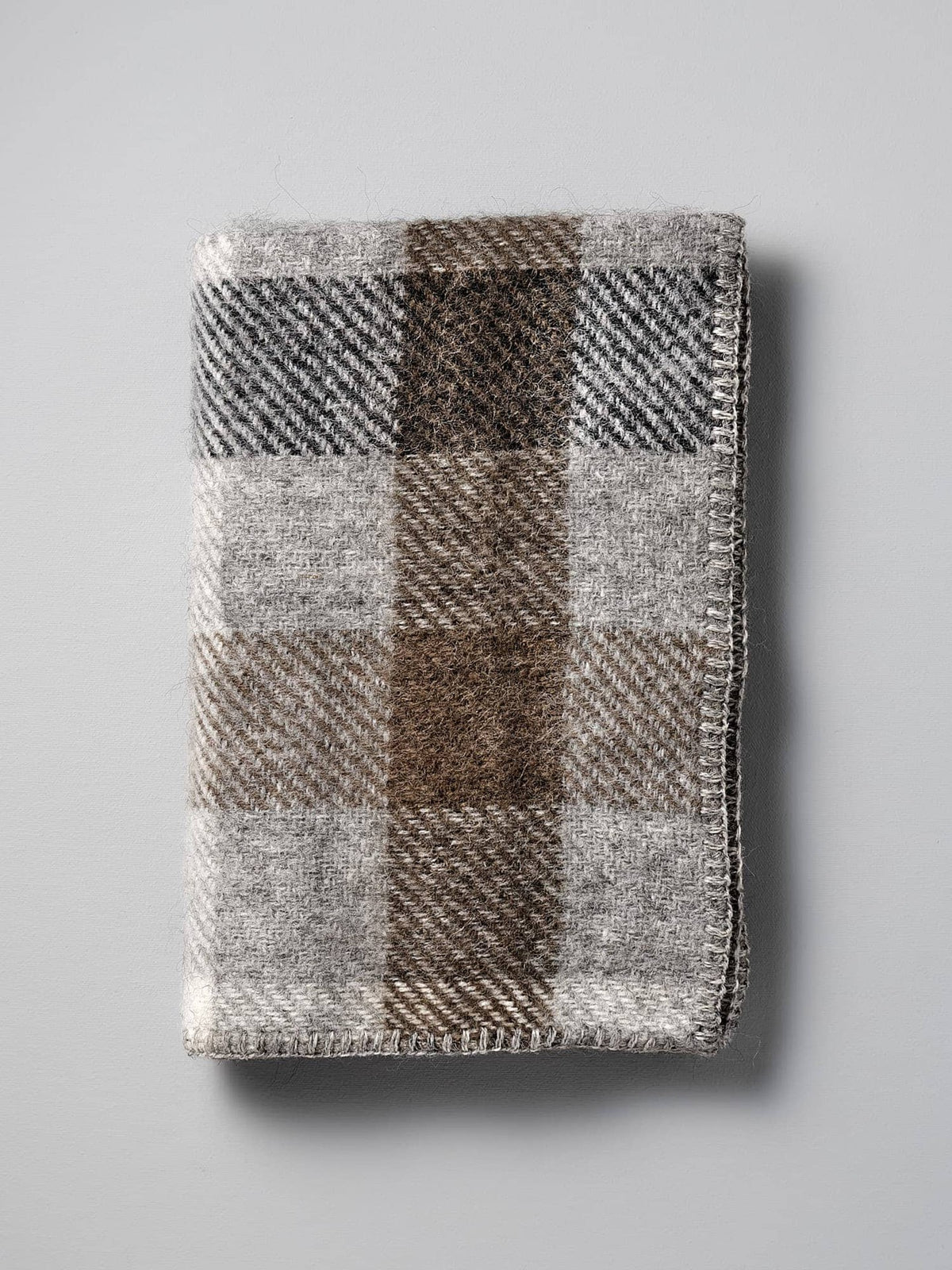 A Klippan Gotland Wool Baby Throw - Multi Grey blanket on a white surface.