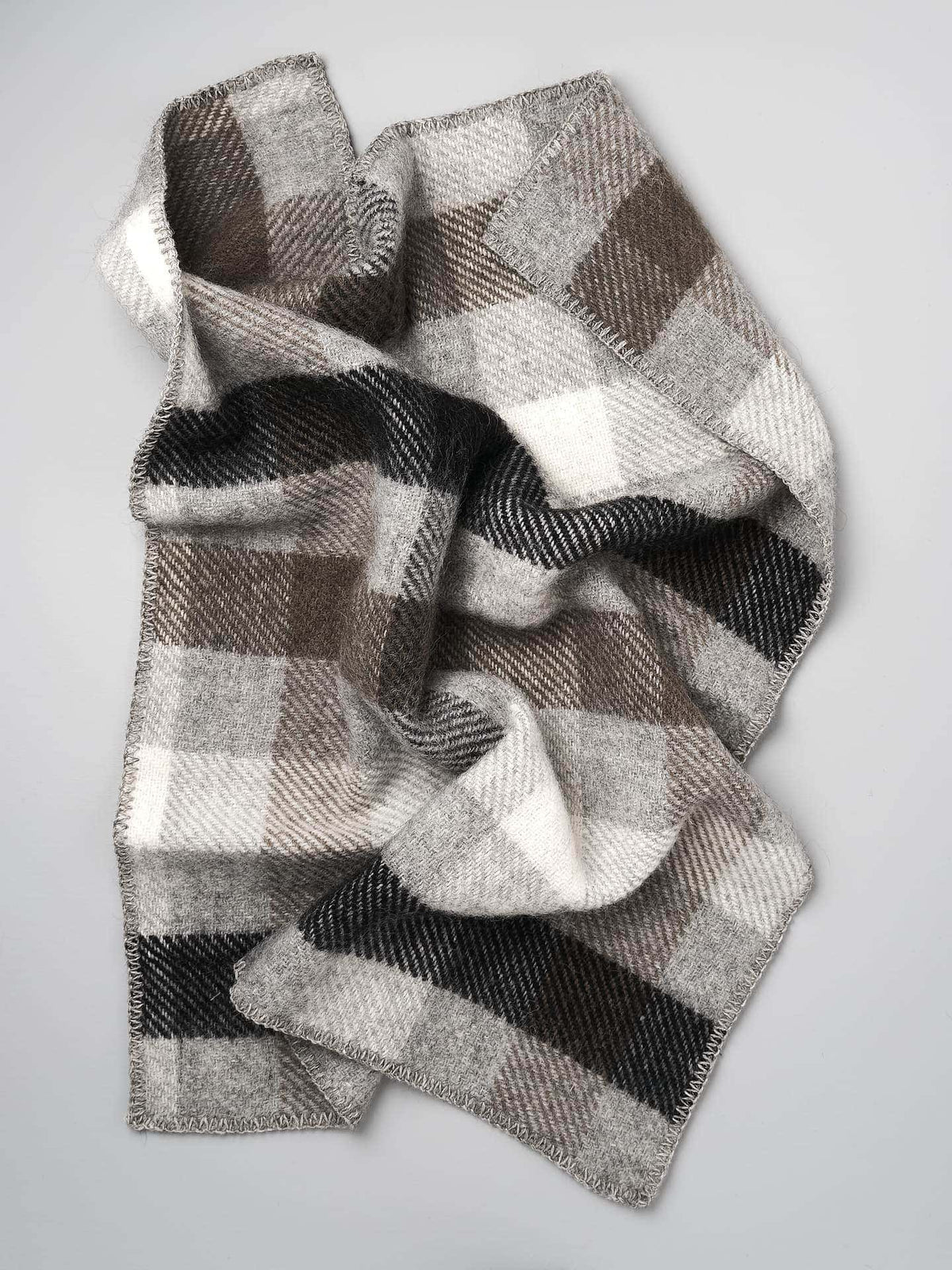 A Klippan Gotland Wool Baby Throw – Multi Grey scarf on a white surface.