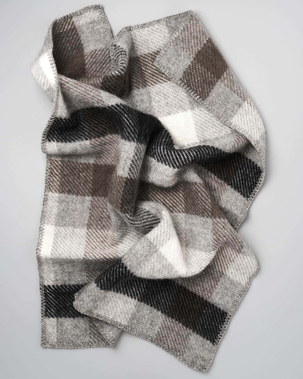 A Klippan Gotland Wool Baby Throw – Multi Grey scarf on a white surface.