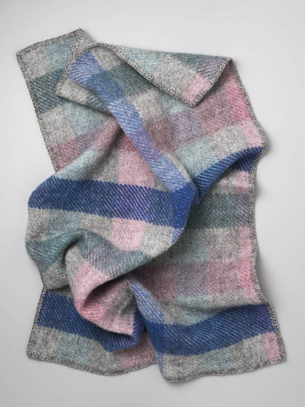 A Klippan Gotland Wool Baby Throw – Multi Pastel blanket on a grey surface.