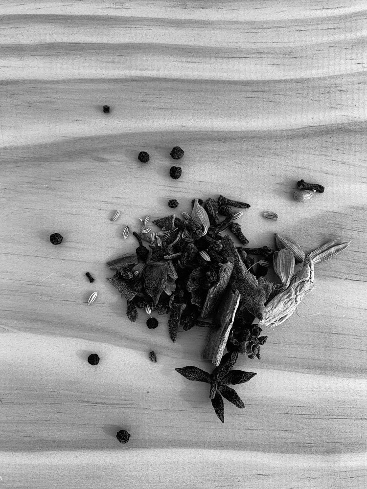 A black and white photo of Ancient Chai by Kaputi Studio dried herbs on a wooden table.