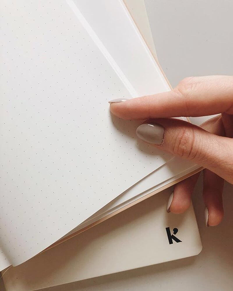 A hand holding a Karst A5 Hardcover Notebook – Eucalypt with the letter k on it.