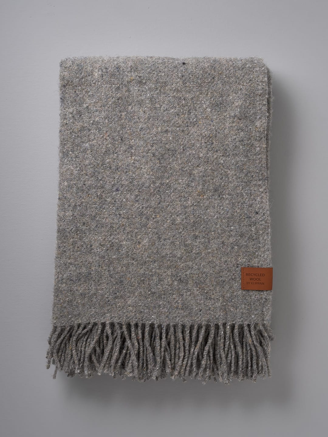 A Klippan Earth Blanket - Grey with fringes on a white background.