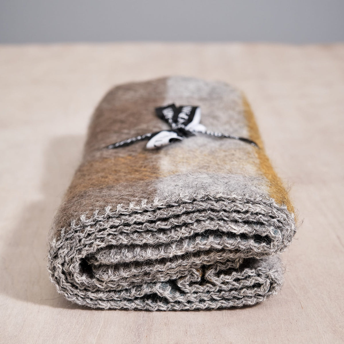A Klippan Gotland Wool Baby Throw – Multi Turquoise blanket on top of a wooden table.