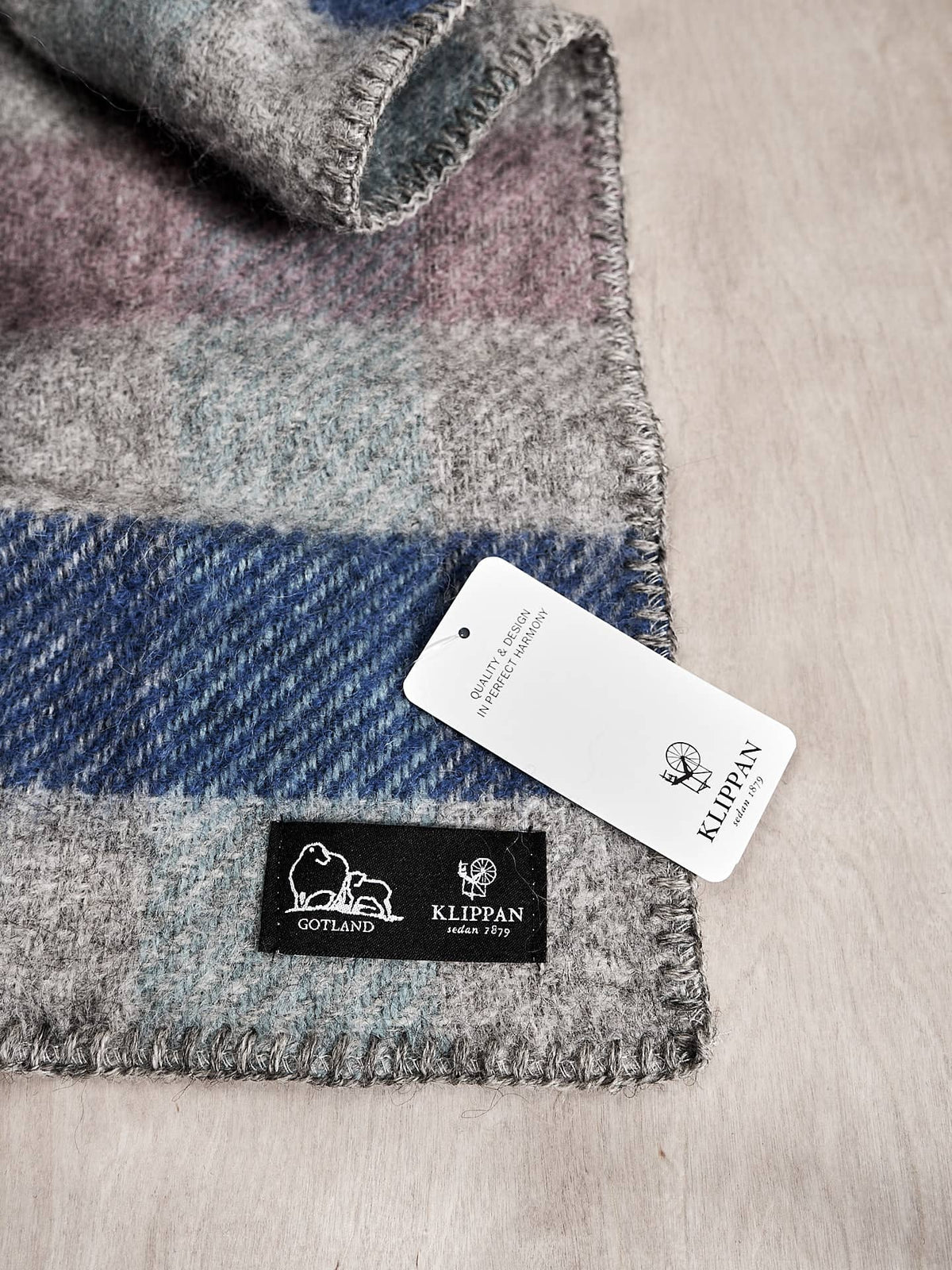 A Klippan Gotland Wool Baby Throw – Multi Pastel blanket with a tag on it.