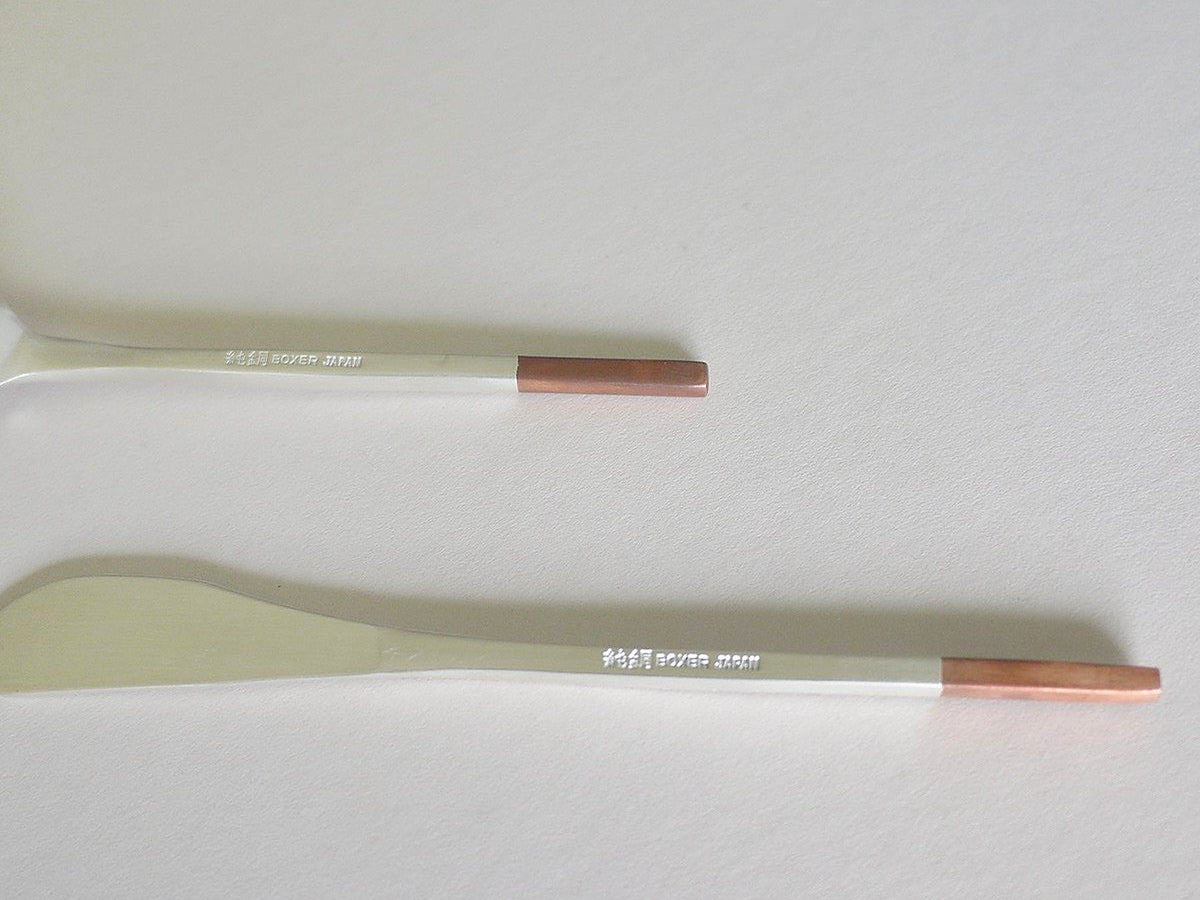 Two Kobo Aizawa Copper and Stainless Steel Teaspoons with copper handles on a white surface.