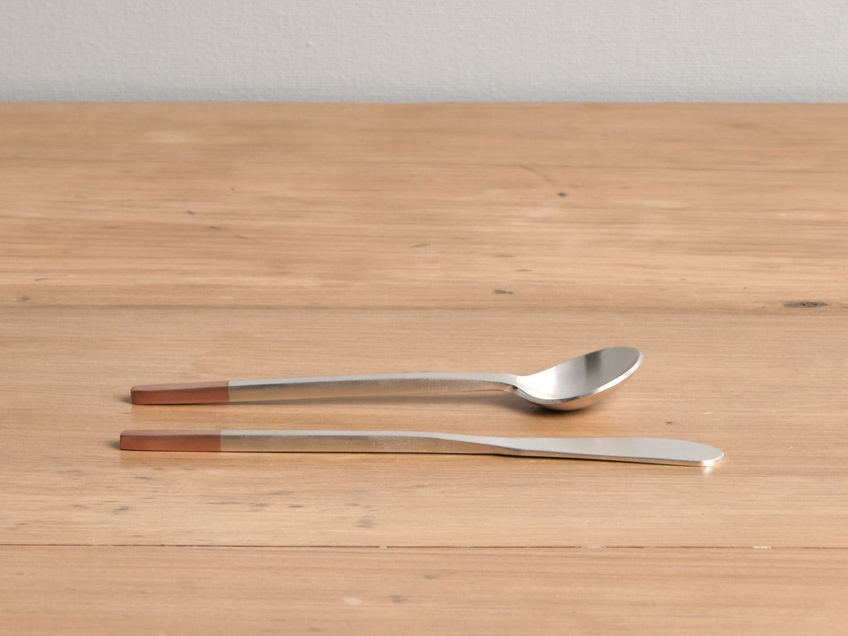 Two Kobo Aizawa Copper and Stainless Steel Teaspoons on a wooden table.