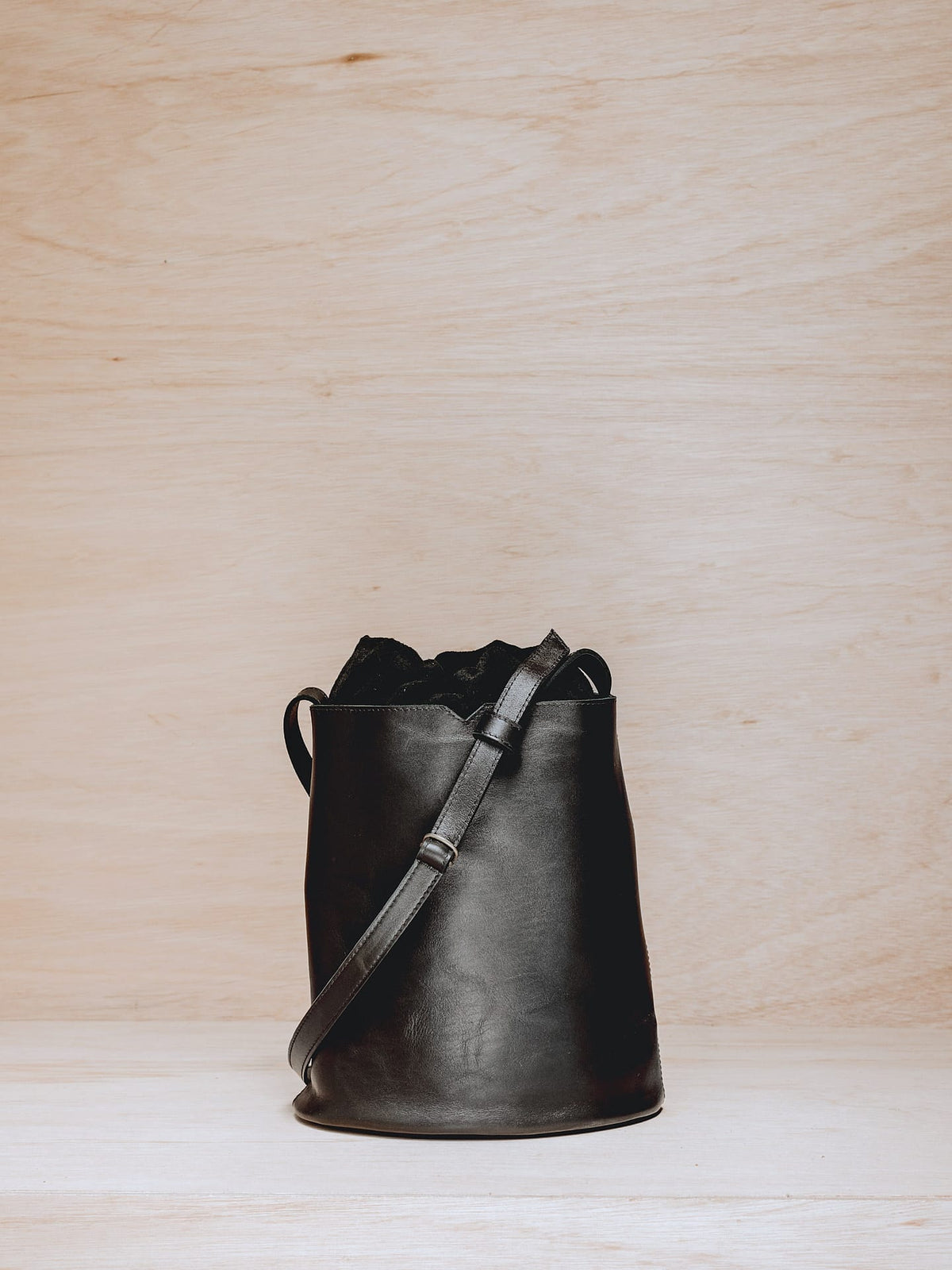 A black Lets Dance bucket bag sitting on top of a wooden table, made by Kohl &amp; Co.