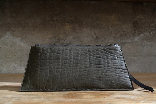 A Maya Clutch – Moss from Kohl &amp; Co on a wooden table.