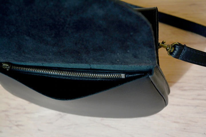 A black leather Cat bag with a zipper on it from Kohl &amp; Co.