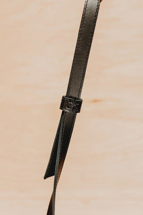 A Side Saddle strap hanging on a wooden surface. (Brand: Kohl &amp; Co)