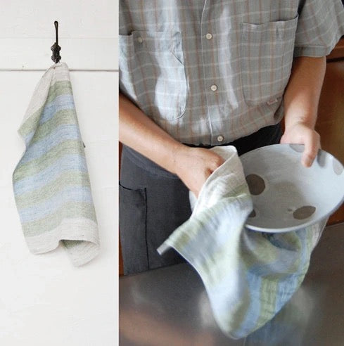A man is holding a Kontex Linen Tea Towel – Yellow or Navy and a bowl.